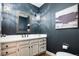 Stylish powder room with a dark blue accent wall, quartz countertop, and decorative chandelier lighting at 7743 S Jersey Way, Centennial, CO 80112