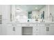 Elegant bathroom vanity featuring double sinks, white cabinets, and decorative mirrors with a geometric tile floor at 7743 S Jersey Way, Centennial, CO 80112