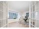 Sunlit office space featuring a glass desk, modern seating, and french doors overlooking the front yard at 7743 S Jersey Way, Centennial, CO 80112