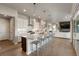 Open-concept kitchen featuring white cabinets, a large island with seating, hardwood floors, and a stainless steel hood at 507 Red Thistle Dr, Highlands Ranch, CO 80126