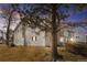 Condo building featuring neutral siding, stone accents, and a mature tree in the front yard under a colorful sunset at 14454 E Colorado Dr # 102, Aurora, CO 80012
