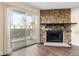 Living room highlighting the stone fireplace, wood flooring, and sliding glass doors to the balcony at 14454 E Colorado Dr # 102, Aurora, CO 80012