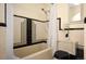 Retro bathroom showcasing a black and cream tile shower with a shower head and floral arrangement on the toilet at 6 Ivy Ln, Denver, CO 80220
