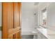 Bright bathroom featuring a shower-over-tub, white tile surround, grey floor and wood-look door at 6246 W 35Th Ave, Wheat Ridge, CO 80033