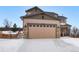 Two-story house with a beige exterior, stone accents, and a three-car garage at 17395 Leisure Lake Dr, Monument, CO 80132