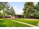 Spacious backyard with mature trees, a brick garage, and lush green lawn at 1035 S Garfield St, Denver, CO 80209