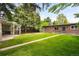 A large backyard is fenced with mature trees, with a grassy lawn and brick home at 1035 S Garfield St, Denver, CO 80209