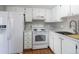 Bright kitchen features white cabinetry and appliances, as well as modern countertops and backsplash at 12743 Eudora Dr, Thornton, CO 80241