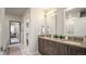 Bathroom with dual sink vanity, modern mirrors, dark wood cabinets, and a view to the main bedroom at 20 Wilcox St # 302, Castle Rock, CO 80104