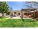 Landscaped backyard featuring a pergola-covered seating area, fire pit, and dining set, ideal for relaxation at 6963 E Heritage S Pl, Centennial, CO 80111