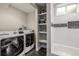 Laundry room with modern washer and dryer, open shelving, and a tiled backsplash at 6963 E Heritage S Pl, Centennial, CO 80111