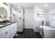 Bathroom with a shower, soaking tub, vanity with double sinks, and black hexagon tiled floor at 1835 S Poplar St, Denver, CO 80224