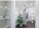 Bright bathroom featuring a tiled walk-in shower, dark hexagonal tiles, and open towel shelving at 1835 S Poplar St, Denver, CO 80224