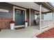 Inviting covered front porch with a gray front door flanked by potted flowers and seating area with a welcome sign at 19935 E Stanford Dr, Centennial, CO 80015