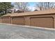 Three single car garages with brown doors sit in a row, offering secure parking and storage space at 1832 S Quintero Way, Aurora, CO 80017