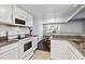 Well-lit kitchen boasts white appliances and granite countertops with a view to the dining area at 1832 S Quintero Way, Aurora, CO 80017