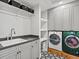 Well-organized laundry room with sleek cabinets, a sink, patterned floors, and modern washer and dryer at 1051 S York St, Denver, CO 80209