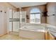 Bathroom with glass shower, soaking tub, and neutral tile at 16350 Timber Cove St, Hudson, CO 80642