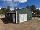 Side view of a large green barn with white doors and trim, set against a rural backdrop at 11840 Elkhorn Dr, Franktown, CO 80116
