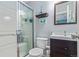 Bathroom featuring glass-doored shower, toilet, dark vanity, and decorative shelf at 5538 Espana Ct, Denver, CO 80249