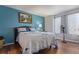 A bedroom featuring blue accent wall, hardwood flooring, and cozy bed with a flower-themed white comforter at 5538 Espana Ct, Denver, CO 80249