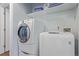 Bright laundry room featuring a modern washer and dryer set with shelving at 5538 Espana Ct, Denver, CO 80249