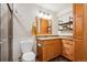 Cozy bathroom featuring granite countertops, wood cabinets, and a tiled shower with glass door at 14434 W 88Th Dr # B, Arvada, CO 80005