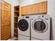 This laundry room features a washer, dryer, storage shelves, and wood cabinets for convenient organization at 14434 W 88Th Dr # B, Arvada, CO 80005