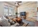 Cozy living room with a wood wall, TV, comfortable sofa, and natural light from the windows at 14434 W 88Th Dr # B, Arvada, CO 80005