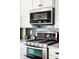 Stainless steel microwave and gas range with a tile backsplash in a modern kitchen at 4738 Colorado River Dr, Firestone, CO 80504