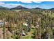 An overhead view showcases a tranquil woodland setting with the house sitting peacefully amongst the towering trees at 10893 Milliken Ave, Conifer, CO 80433