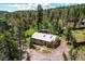 Aerial shot of home surrounded by lush trees with a metal roof and chimney at 10893 Milliken Ave, Conifer, CO 80433