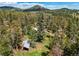 An aerial shot displays the house surrounded by tall trees, creating a sense of peaceful seclusion and immersion in nature at 10893 Milliken Ave, Conifer, CO 80433