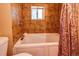 Bathroom with tub and shower combination, accented by warm-toned tiles and natural light from the window at 10893 Milliken Ave, Conifer, CO 80433