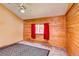 Bedroom featuring wooden paneling, window with red curtain, and carpet at 10893 Milliken Ave, Conifer, CO 80433