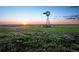 Scenic meadow with a vintage windmill, bench, and sunset backdrop, creating a serene vista at 39743 Penn Rd, Elizabeth, CO 80107
