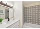 Stylish bathroom with quartz counters, patterned tile, modern fixtures, and a tub with tiled walls at 8622 W Warren Ln, Lakewood, CO 80227