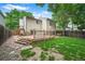 Well-maintained backyard with a wooden deck, lush lawn, and mature trees offering privacy and shade at 5602 S Yank Ct, Littleton, CO 80127