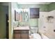 Hall bathroom with green walls, bathtub with tile surround, modern lighting and plenty of storage space at 5602 S Yank Ct, Littleton, CO 80127