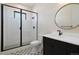Modern bathroom featuring a walk-in shower, round mirror, geometric floor tiles, and a dark vanity at 5741 Doc Bar Circle, Larkspur, CO 80118