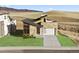 Contemporary stone home featuring a two-car garage and beautifully landscaped front yard, situated on a hill at 5741 Doc Bar Circle, Larkspur, CO 80118