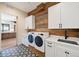 A laundry room with a rustic wood accent wall, patterned tile floor, and modern white washer and dryer units at 5741 Doc Bar Circle, Larkspur, CO 80118