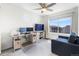 Bright bedroom featuring neutral walls, a ceiling fan, and a dedicated workspace with monitors and a blue sofa at 16362 E 111Th Dr, Commerce City, CO 80022