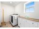 Well-lit laundry room featuring modern washer and dryer, complemented by functional white cabinets and wood countertop at 16362 E 111Th Dr, Commerce City, CO 80022