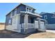 Attractive two-story home with gray siding, white accents, a covered porch with stone supports, and an attached two-car garage at 11024 Snowdon St, Parker, CO 80134