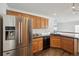 Modern kitchen with stainless steel refrigerator, black countertops, and wood cabinets at 5202 Cathay St, Denver, CO 80249