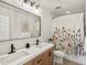 Bathroom featuring double sinks, wood vanity, framed mirror, and decorative floral shower curtain at 800 Boulder Peak Ave, Erie, CO 80516