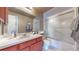 Well-maintained bathroom featuring a vanity with storage, a mirror, and a shower-tub combination with sliding glass doors at 11813 Bellaire Cir, Thornton, CO 80233