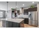 Modern kitchen featuring stainless steel appliances, dark cabinets, and a large center island with a white countertop at 14035 Touchstone St, Parker, CO 80134