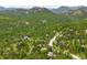 Expansive aerial view of a neighborhood nestled among mature trees and mountains in the background at 29962 Troutdale Ridge Rd, Evergreen, CO 80439